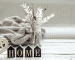 Still life in hygge style with the wooden word home, decor details and a knitted element. The concept of home comfort and modern style.